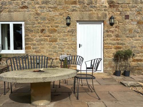 a patio with a table and chairs in front of a building at Bank Cottage in Grindleford Bridge