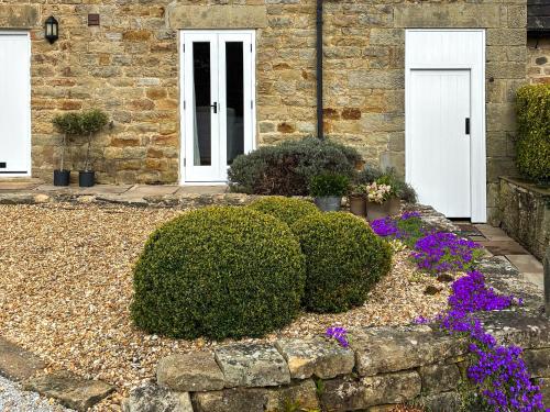 a house with two white doors and purple flowers at Bank Cottage in Grindleford Bridge
