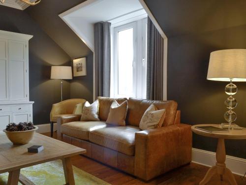a living room with a leather couch and a window at Darroch View in Ballater