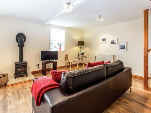 a living room with a leather couch and a fireplace at Hall Farm Cottage in Byers Green