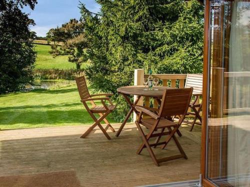 a wooden table and chairs on a patio at Henning Lodge - Uk31008 in Ansty