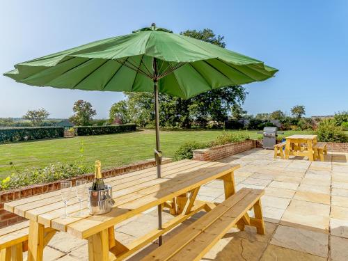 a picnic table with a green umbrella on a patio at Pattiswick Hall in Stisted