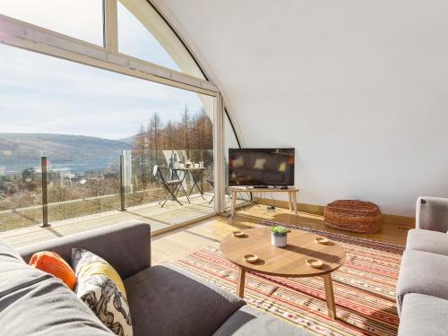 a living room with a couch and a large window at Jill Strawbale House- Ukc2935 in Strontian