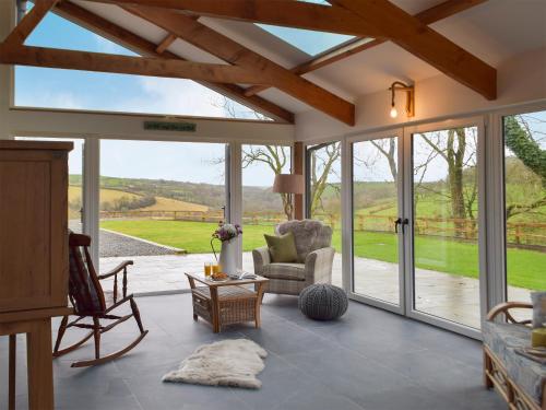 a living room with large windows and a couch and chairs at Cwm Hyfryd in Llanboidy