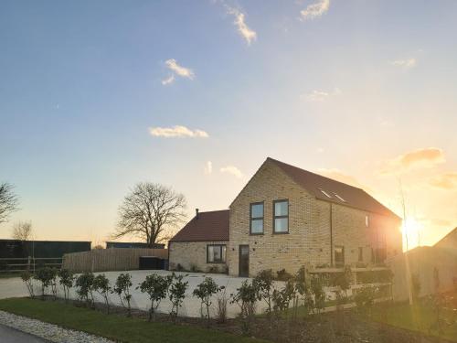 a brick house with the sun setting behind it at The Willows - Ukc4617 in Dunholme