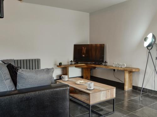 a living room with a couch and a table with a television at Caffi Sali - Weluk143 in Blaenpenal