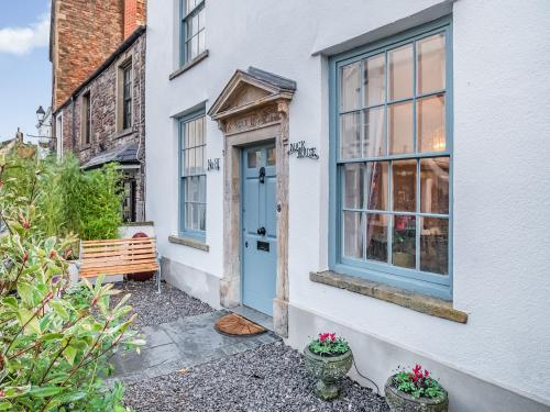a white house with a blue door and a bench at Rock House in Wells
