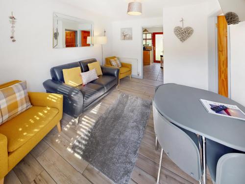a living room with yellow and black furniture and a table at Elm Cottage-Uk2791 in Penmaen-mawr
