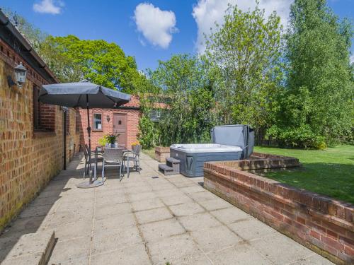 a patio with a table and a grill and an umbrella at Beech Barns - Czu in Neatishead