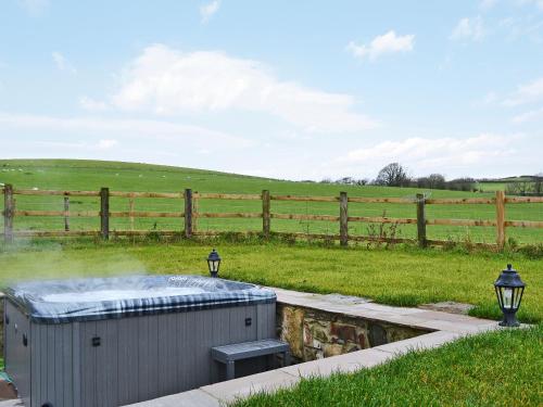 a hot tub in a field next to a fence at Bluebell Barn in Okehampton