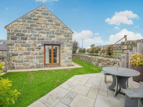 a stone house with a table in the yard at Deri Cottage in Chwilog