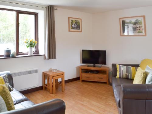 a living room with a couch and a flat screen tv at Sunset in Cheriton Bishop