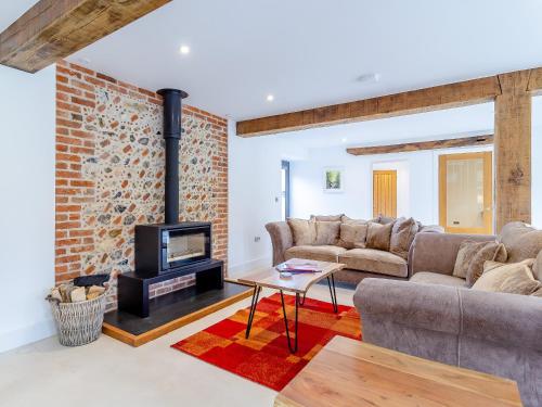 a living room with a fireplace and a brick wall at Kestrel Barn-Uk31353 in Swaffham