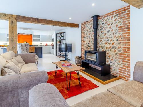 a living room with a fireplace and a brick wall at Kestrel Barn-Uk31353 in Swaffham