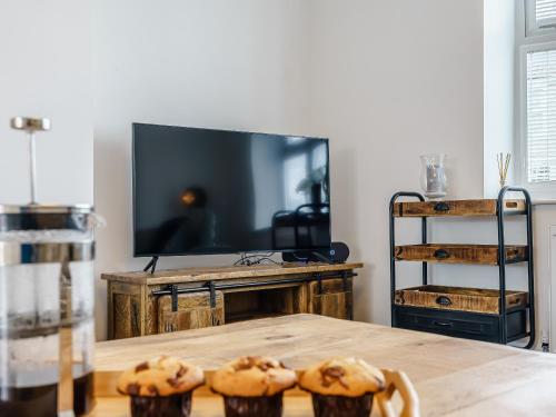 a table with three muffins on it in front of a television at Wynbec Cottage in Esh