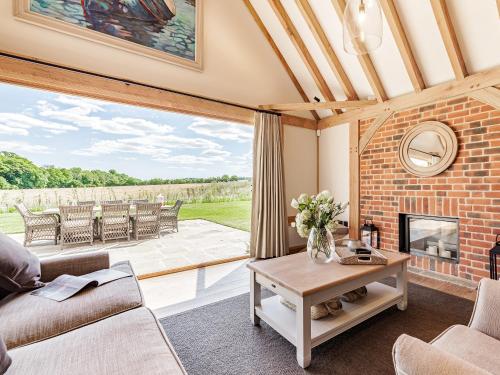 a living room with a fireplace and a patio at Lovington Barn in Ovington