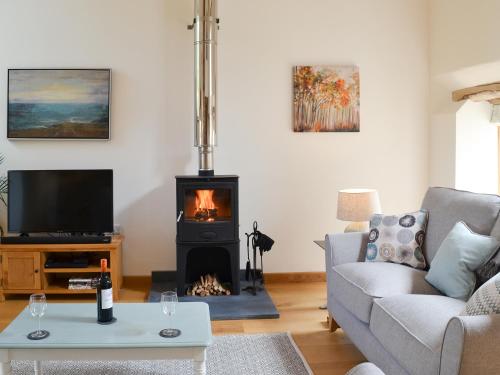 a living room with a fireplace and a tv at The Oak Stall - Uk11023 in East Worlington
