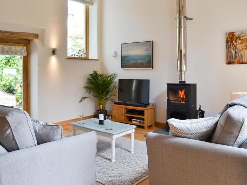 a living room with two couches and a tv and a stove at The Oak Stall - Uk11023 in East Worlington