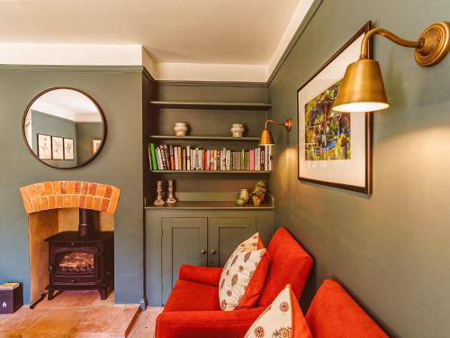 a living room with a red couch and a fireplace at Gatehouse North in Worstead