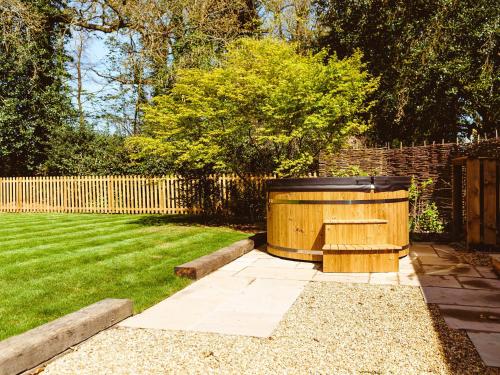 a wooden hot tub in a yard with a fence at Gatehouse North in Worstead