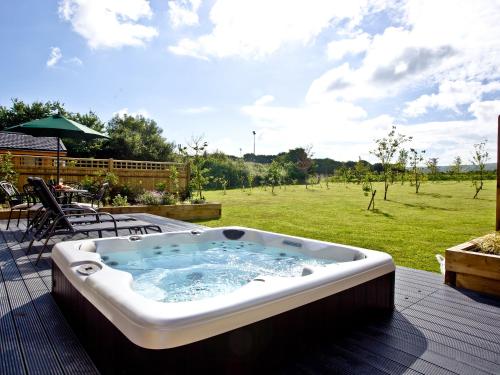 a jacuzzi tub on a deck with a field at Holly Lodge in Hassocks