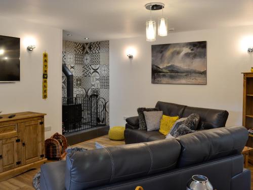 a living room with a black leather couch at Bryn Aled in Llanfachreth