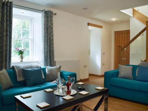 a living room with blue couches and a table at Waterloo Farm House in Bankfoot