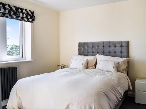 a white bedroom with a large bed with white pillows at Kinneret Apartment in Silsden