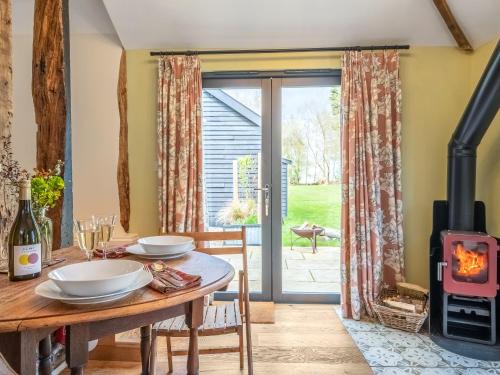a wood burner in a dining room with a table and a fireplace at The Old Press - Uk50806 in Halesworth
