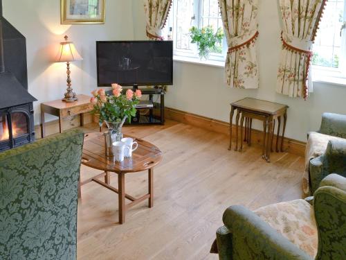 a living room with a fireplace and a table with flowers at The Appleloft in Westleigh