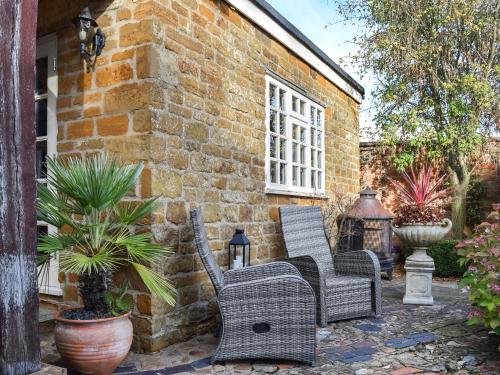 two wicker chairs sitting outside of a brick building at Russell Cottage in Flore