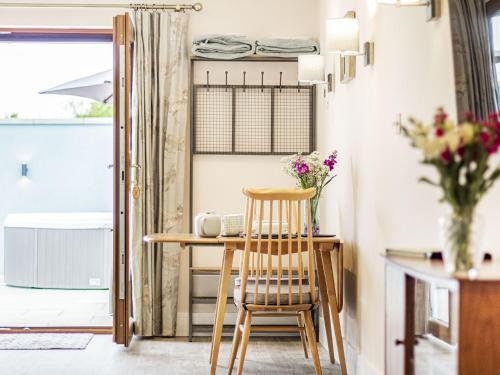 a small table and chair in a kitchen with flowers at Wisteria Lodge - Ukc5804 in Shelfanger