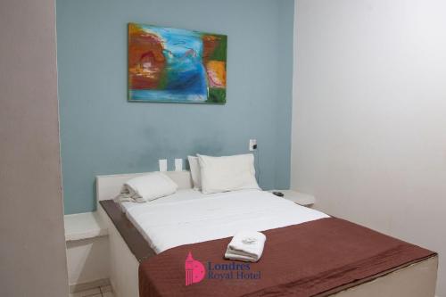 a bed in a room with a painting on the wall at Londres Royal Hotel - Cama de alvenaria in Londrina