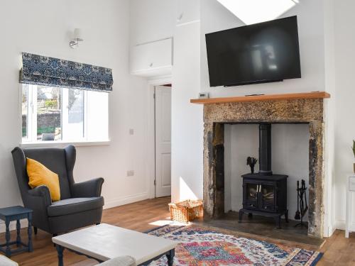 a living room with a fireplace with a tv above it at Rose Cottage in Bardon Mill