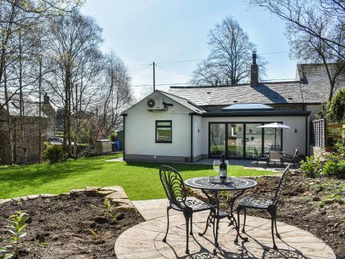 a patio with a table and chairs in front of a house at Rose Cottage in Bardon Mill