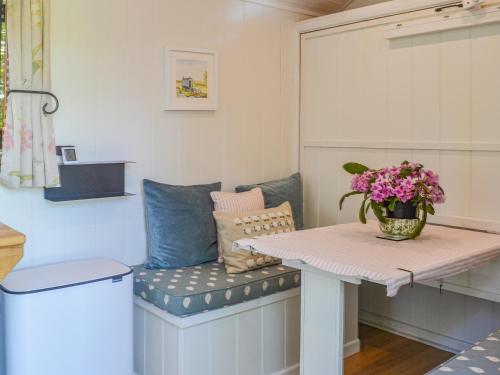 a room with a table and a bench with flowers on it at Herdwick Hut Mountain Retreat in Twyn Llanan