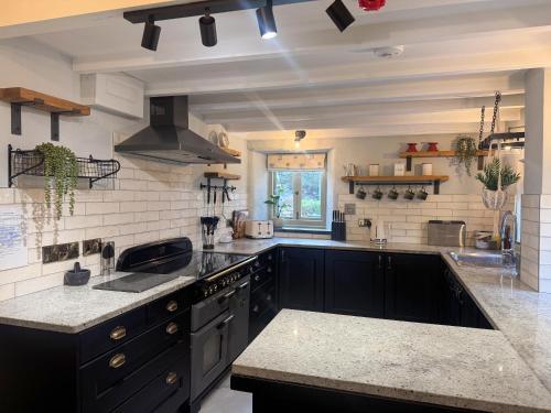 a large kitchen with black cabinets and a sink at Bluebell Cottage in Bodmin