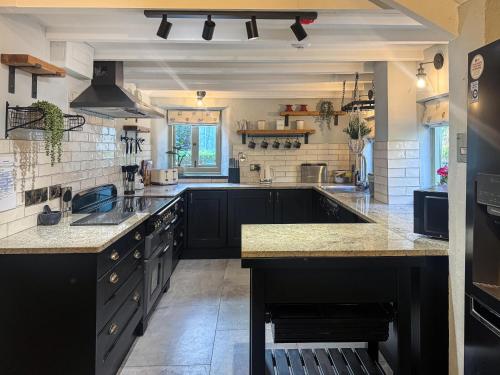 a kitchen with black cabinets and granite counter tops at Bluebell Cottage in Bodmin