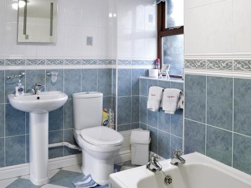 a bathroom with a toilet and a sink and a tub at Ysgubor in Harlech