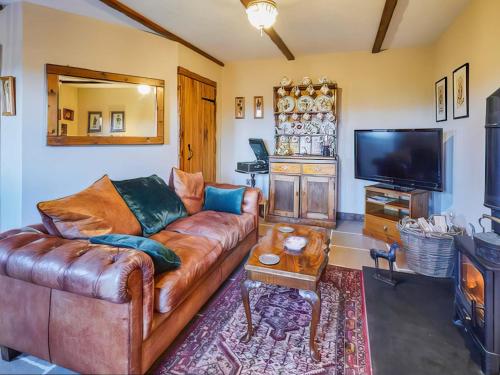 a living room with a leather couch and a flat screen tv at Rustic Retreat in Llangadog