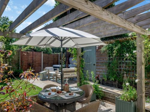 a patio with a table and an umbrella at Hope Cottage in Ilketshall Saint Andrew