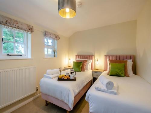two beds in a room with green and white at Oak Tree Cottage in Quidenham