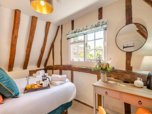 a bedroom with a bed and a mirror and a sink at Oak Tree Cottage in Quidenham