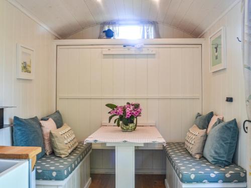 a small room with two benches and a table with flowers at Herdwick Hut Mountain Retreat in Twyn Llanan