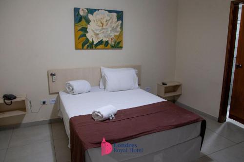 a bedroom with a bed with towels on it at Londres Royal Hotel in Londrina