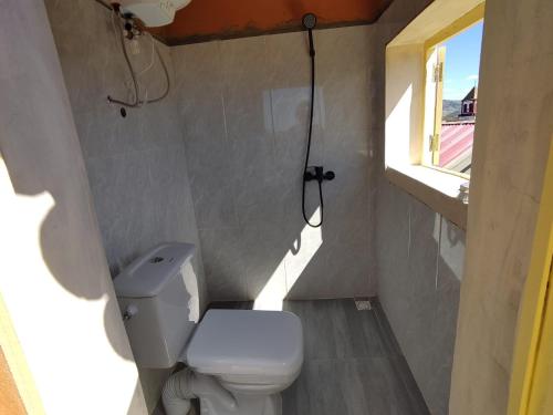 a small bathroom with a toilet and a window at Chez Julienne in Fianarantsoa