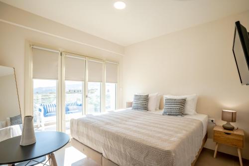 a white bedroom with a bed and a window at Apeiron Akrotiri - Apeiron Hotels in Akrotiri