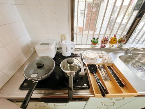 a kitchen stove with a frying pan on top of it at LUMI HOUSE 101, 8 minutes to Namba 4 minutes walk to the station self check in in Osaka