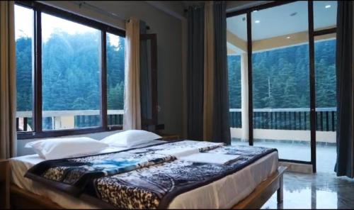 a bedroom with a bed with a large window at Hotal DESPRADES MRITYUNJAY INN in Jageshwar