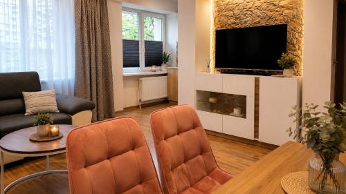 a living room with a television and a couch and a table at Centro apartamentai in Zarasai